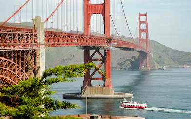 Golden Gate Bridge with a cruise boat passing underneath in San Francisco Bay.