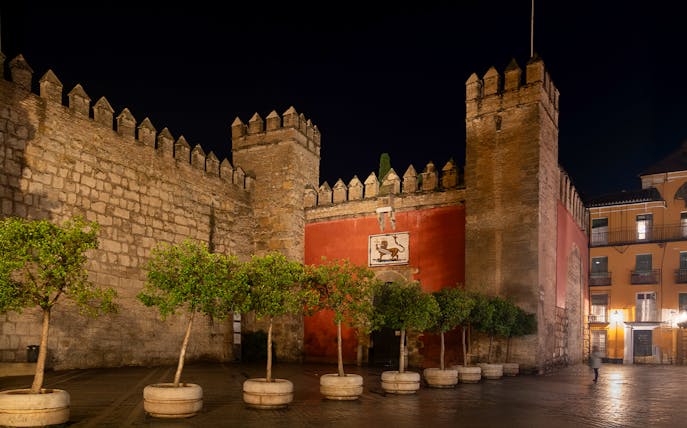 Puerta del León entrance to Royal Alcazar in Seville, Spain, illuminated at night.