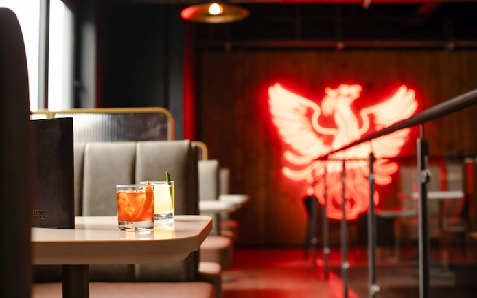 Teeling Whiskey Distillery interior with cocktails and neon phoenix sign.