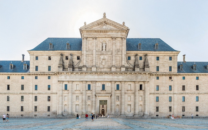El Escorial courtyard with visitors in front of the historic facade, Spain.