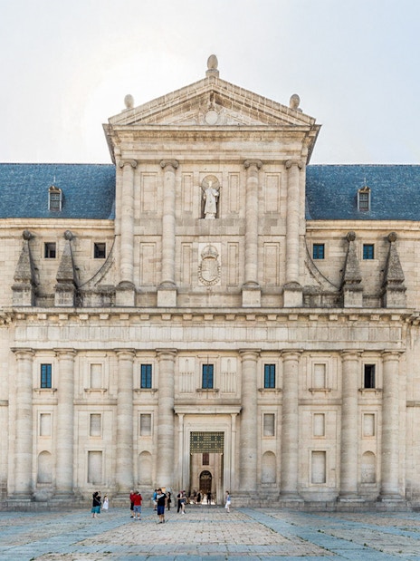 El Escorial courtyard with visitors in front of the historic facade, Spain.