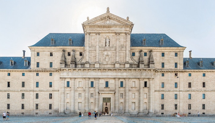 El Escorial courtyard with visitors in front of the historic facade, Spain.