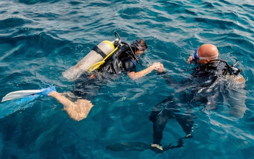 Diving instructor guiding tourist underwater in Ibiza.