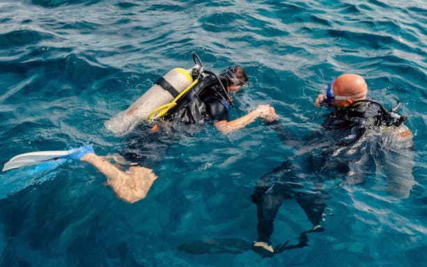 Diving instructor guiding tourist underwater in Ibiza.