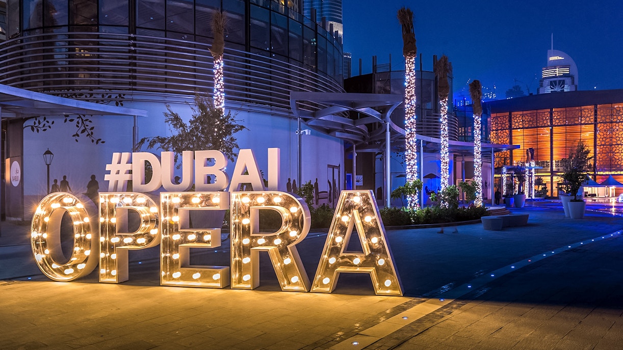 Dubai Opera entrance illuminated at night, featuring large lit-up letters.