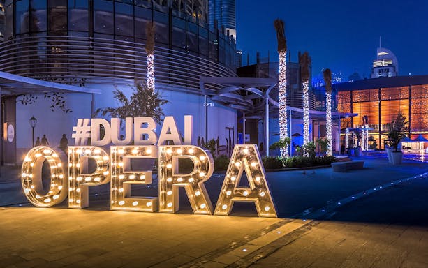 Dubai Opera entrance illuminated at night, featuring large lit-up letters.