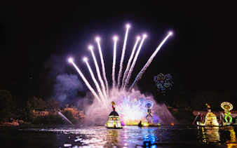 Nighttime FiestAventura show with fireworks over the lake in PortAventura, Spain.