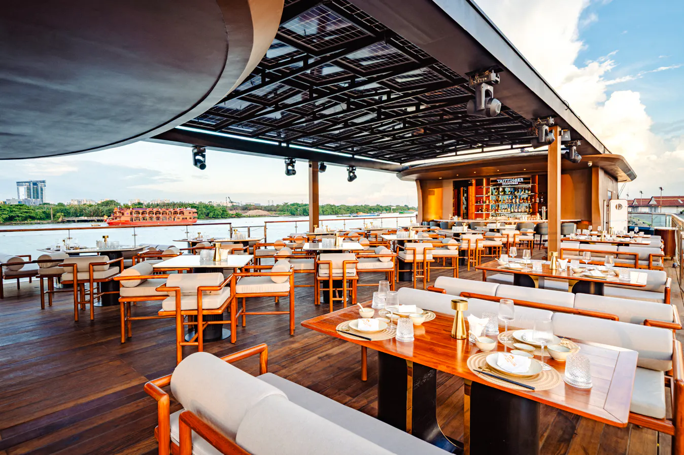Riverside dining area on a cruise ship in Ho Chi Minh City with tables set for dinner.