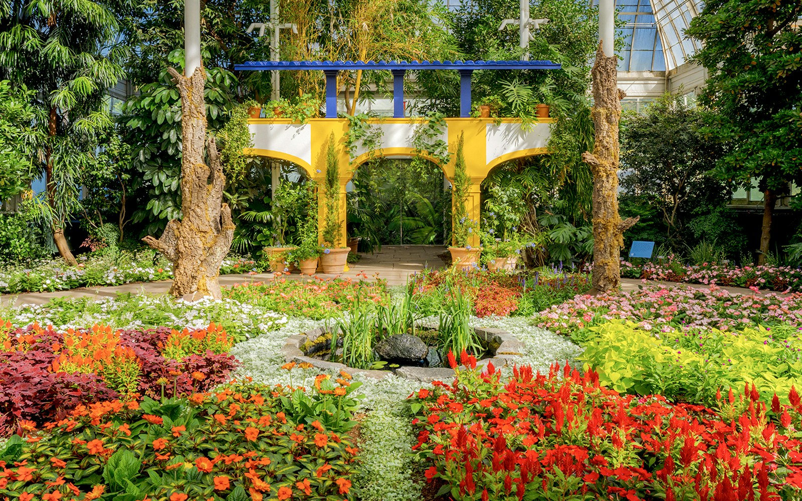 Visitors exploring lush greenery inside New York Botanical Garden's conservatory.