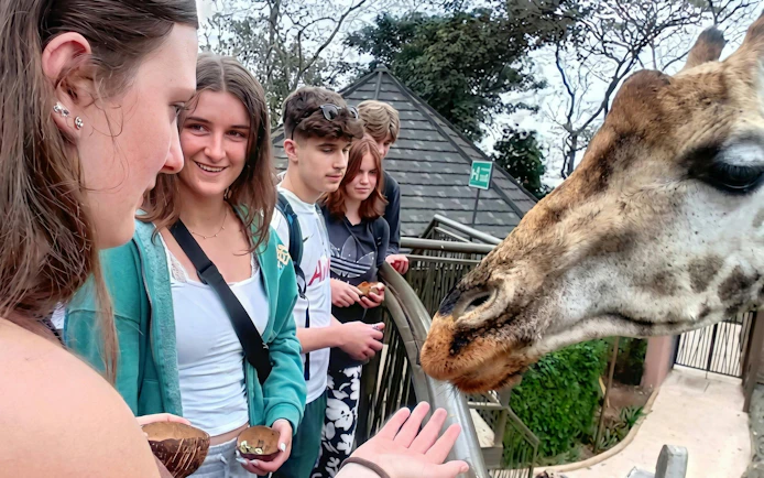 Woman feeding giraffe at Giraffe Centre, Nairobi with others watching.