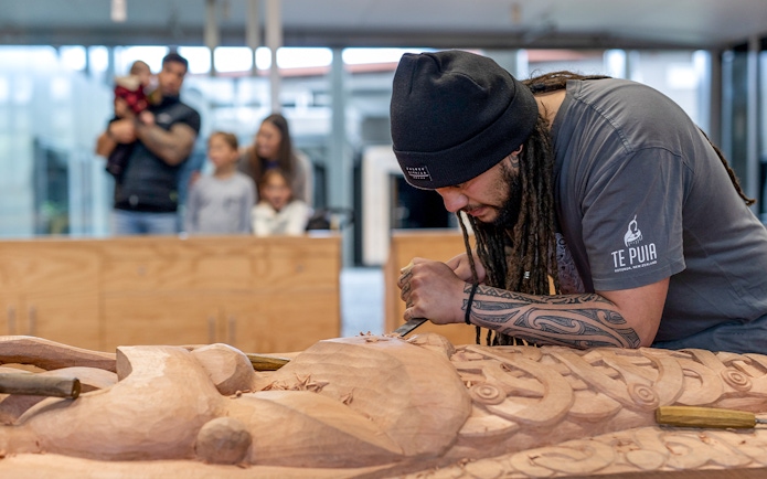 Carver working on Māori wood sculpture at Te Puia, Rotorua, New Zealand.