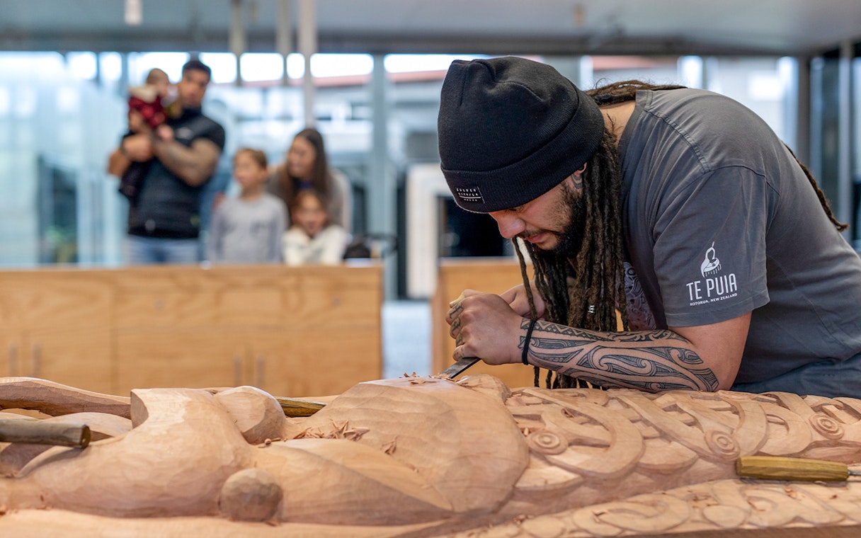 Carver working on Māori wood sculpture at Te Puia, Rotorua, New Zealand.