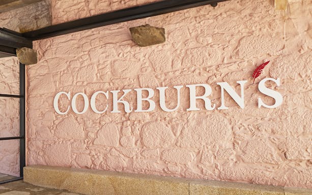 Cockburn's sign on a textured pink wall, related to French tour and Super Premium tasting.