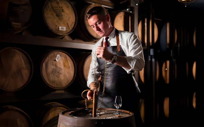 Man blending whiskey at Jameson Distillery Black Barrel class, surrounded by barrels.