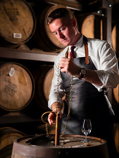 Man blending whiskey at Jameson Distillery Black Barrel class, surrounded by barrels.