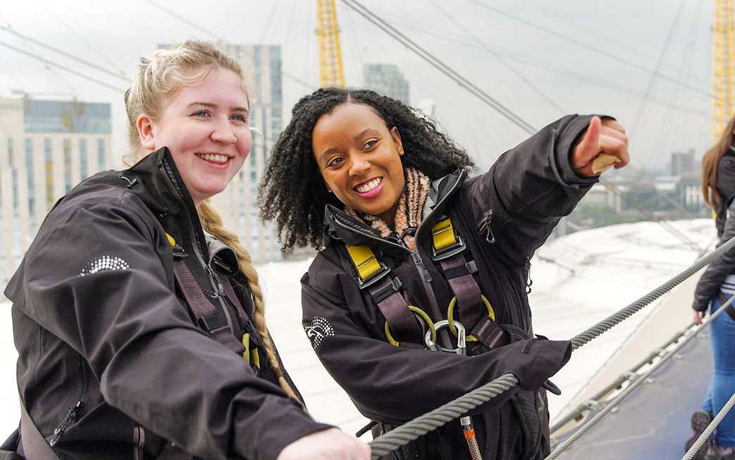 Guide pointing while talking to tourist on rooftop tour in London.