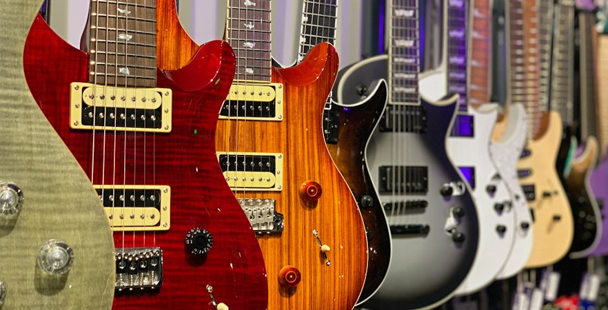 Row of electric guitars on display at a guitar museum.