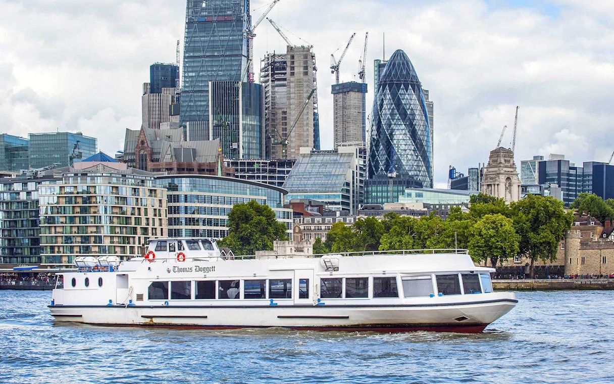 River cruise boat on the Thames with London skyline, including the Gherkin, in the background.