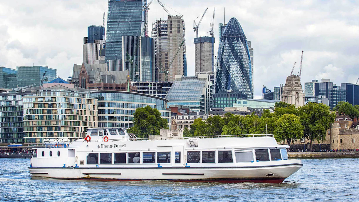 River cruise boat on the Thames with London skyline, including the Gherkin, in the background.
