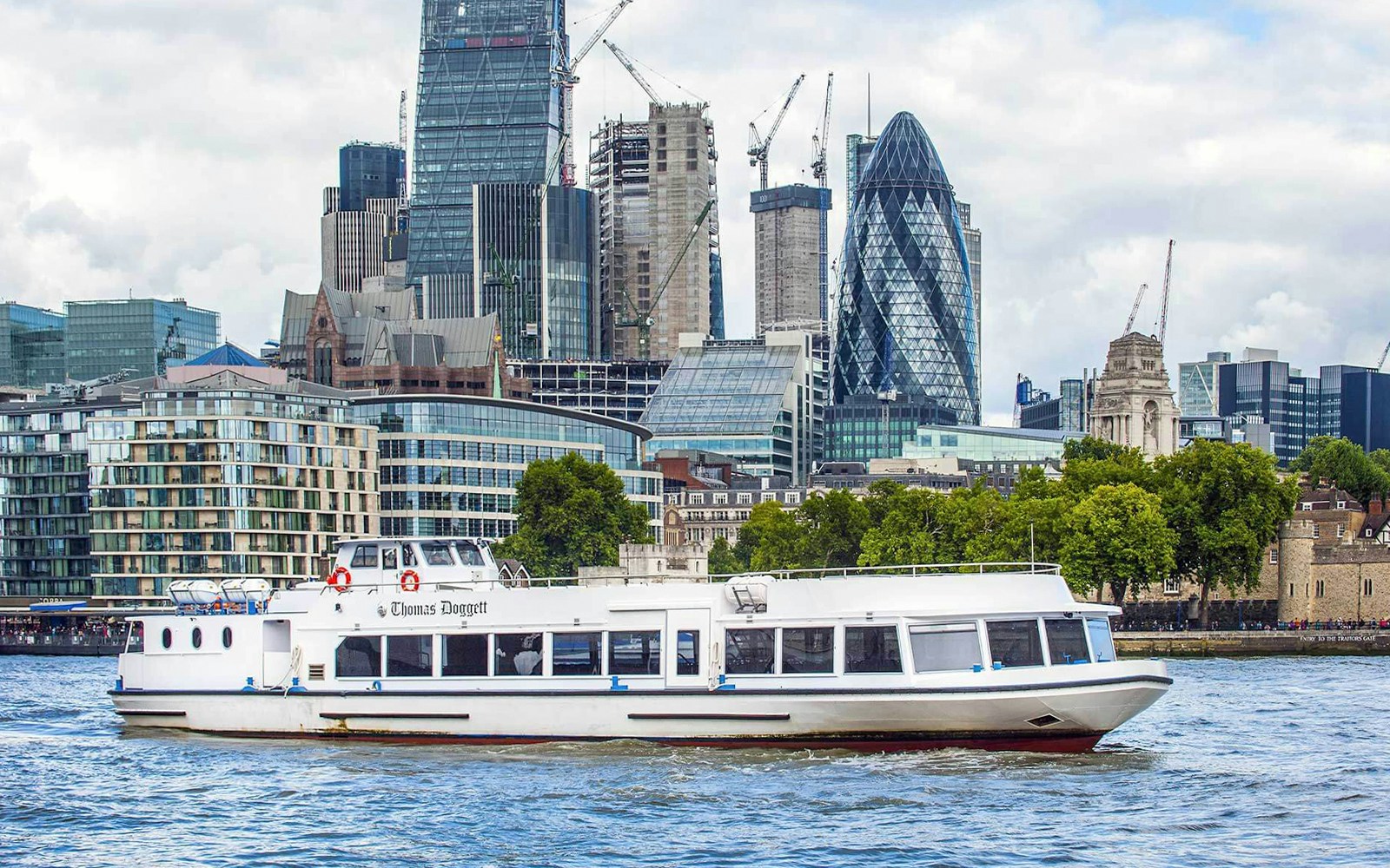 River cruise boat on the Thames with London skyline, including the Gherkin, in the background.