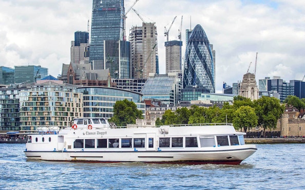 River cruise boat on the Thames with London skyline, including the Gherkin, in the background.