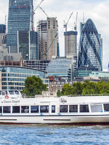 River cruise boat on the Thames with London skyline, including the Gherkin, in the background.