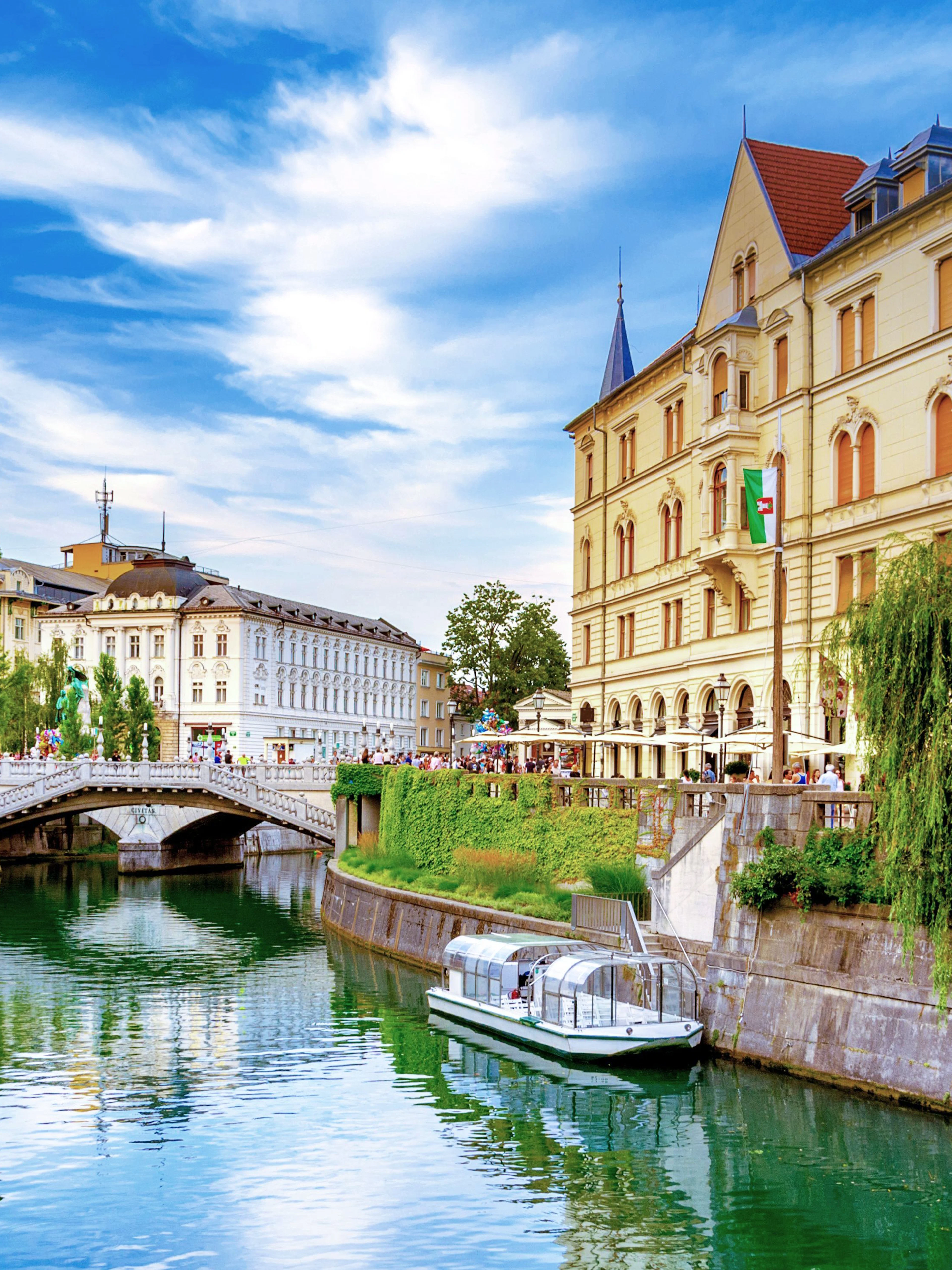 Tromostovje bridge over Ljubljanica River in Ljubljana, Slovenia, with riverside cafes and historic buildings.