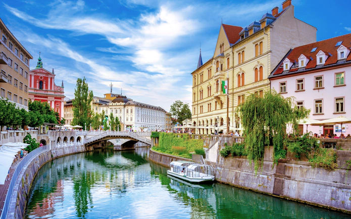 Tromostovje bridge over Ljubljanica River in Ljubljana, Slovenia, with riverside cafes and historic buildings.