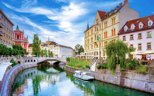 Tromostovje bridge over Ljubljanica River in Ljubljana, Slovenia, with riverside cafes and historic buildings.