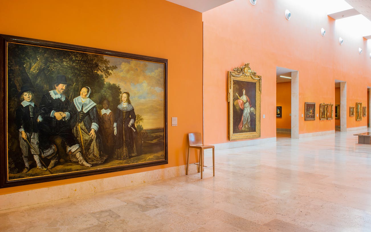 Thyssen Museum gallery with classic art paintings on orange walls.