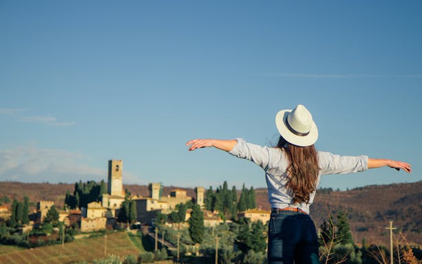 Woman enjoying view of Tuscan village during VIP Semi-Private Wineland Safari from Florence.