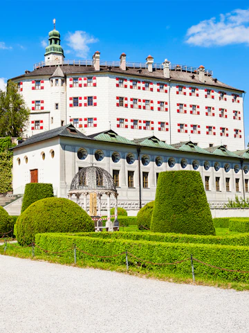 Ambras Castle in Innsbruck with manicured gardens and historic architecture.