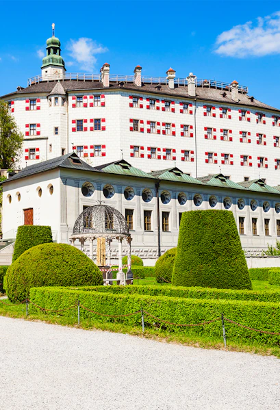 Ambras Castle in Innsbruck with manicured gardens and historic architecture.