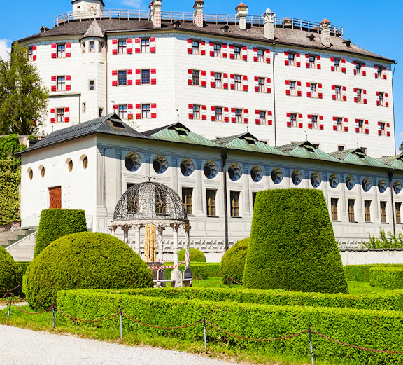 Ambras Castle in Innsbruck with manicured gardens and historic architecture.