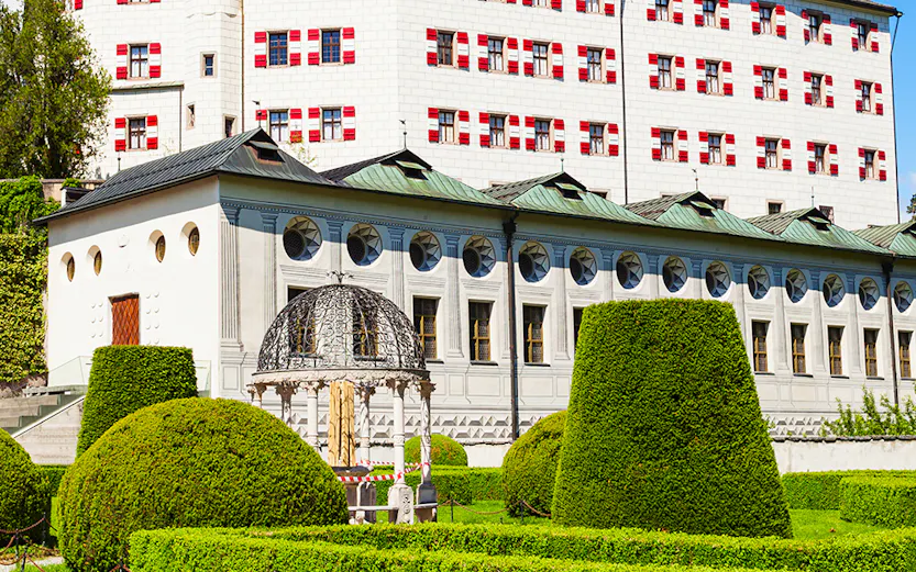Ambras Castle in Innsbruck with manicured gardens and historic architecture.