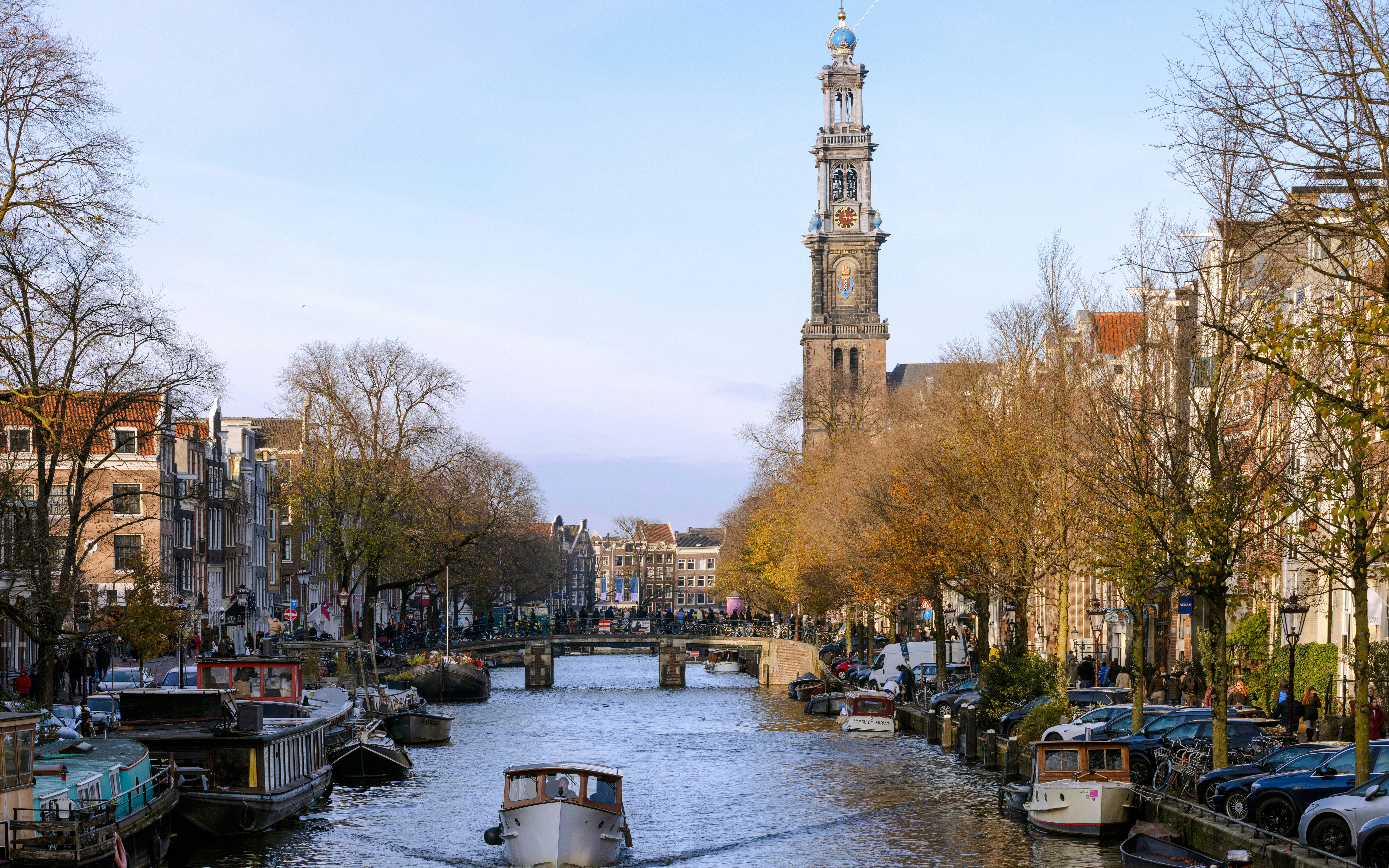 Tourist boat on Prinsengracht canal with Westerkerk tower, Amsterdam in spring.
