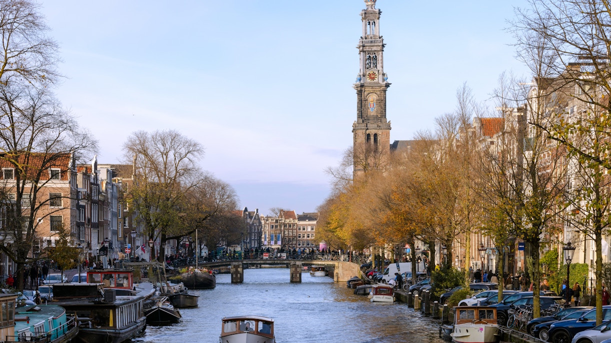 Tourist boat on Prinsengracht canal with Westerkerk tower, Amsterdam in spring.