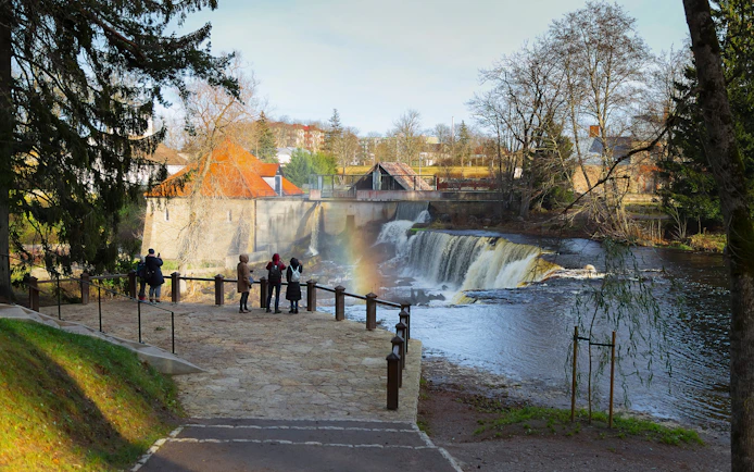 Visitors viewing Keila Waterfall with rainbow in Northern Estonia.