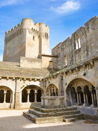 Abbey of Montmajour courtyard with stone arches and historic tower in Arles, France.