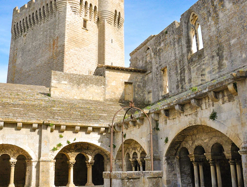 Abbey of Montmajour courtyard with stone arches and historic tower in Arles, France.