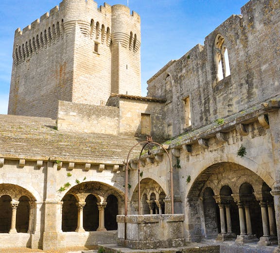 Abbey of Montmajour courtyard with stone arches and historic tower in Arles, France.