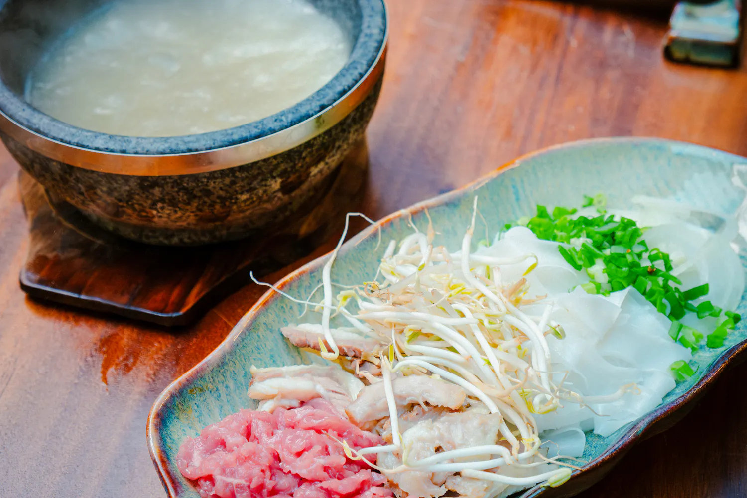 Stone bowl with pho ingredients and broth for cooking class in Hanoi.