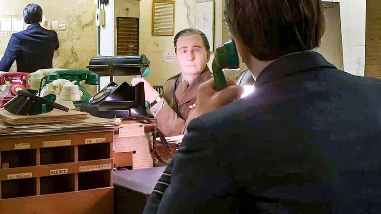 Man in military uniform at desk with vintage telephones, Churchill War Rooms tour.