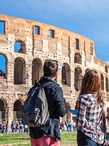 Tourists with backpacks exploring the Colosseum in Rome using the Rome Super Pass.