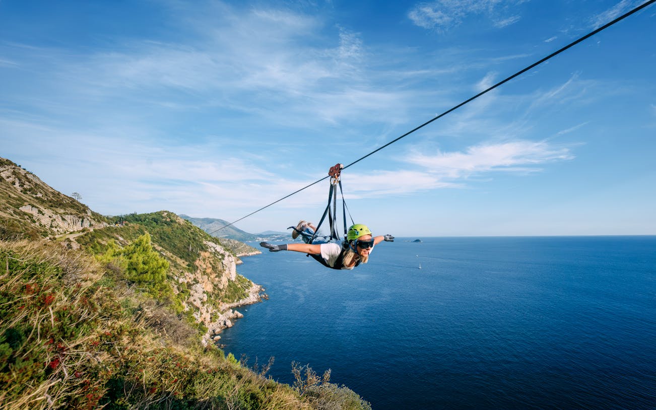 Zip lining over Pasjača Beach, Croatia with coastal views.