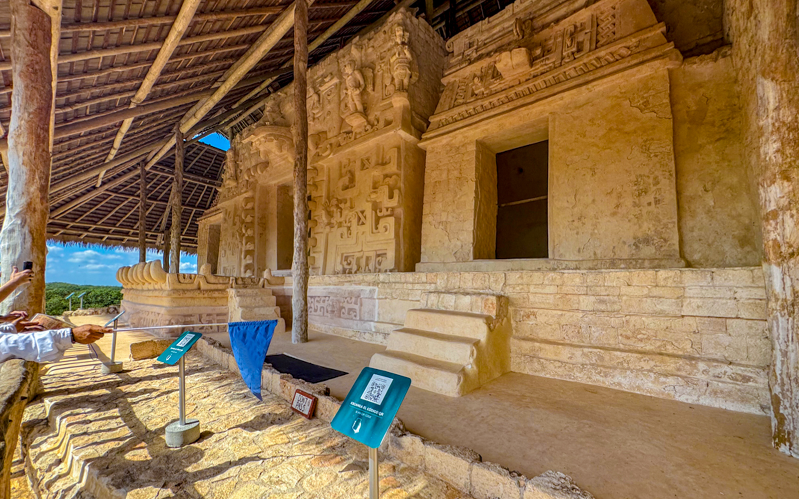 Ek Balam archaeological site with ancient stone carvings and steps under a thatched roof.