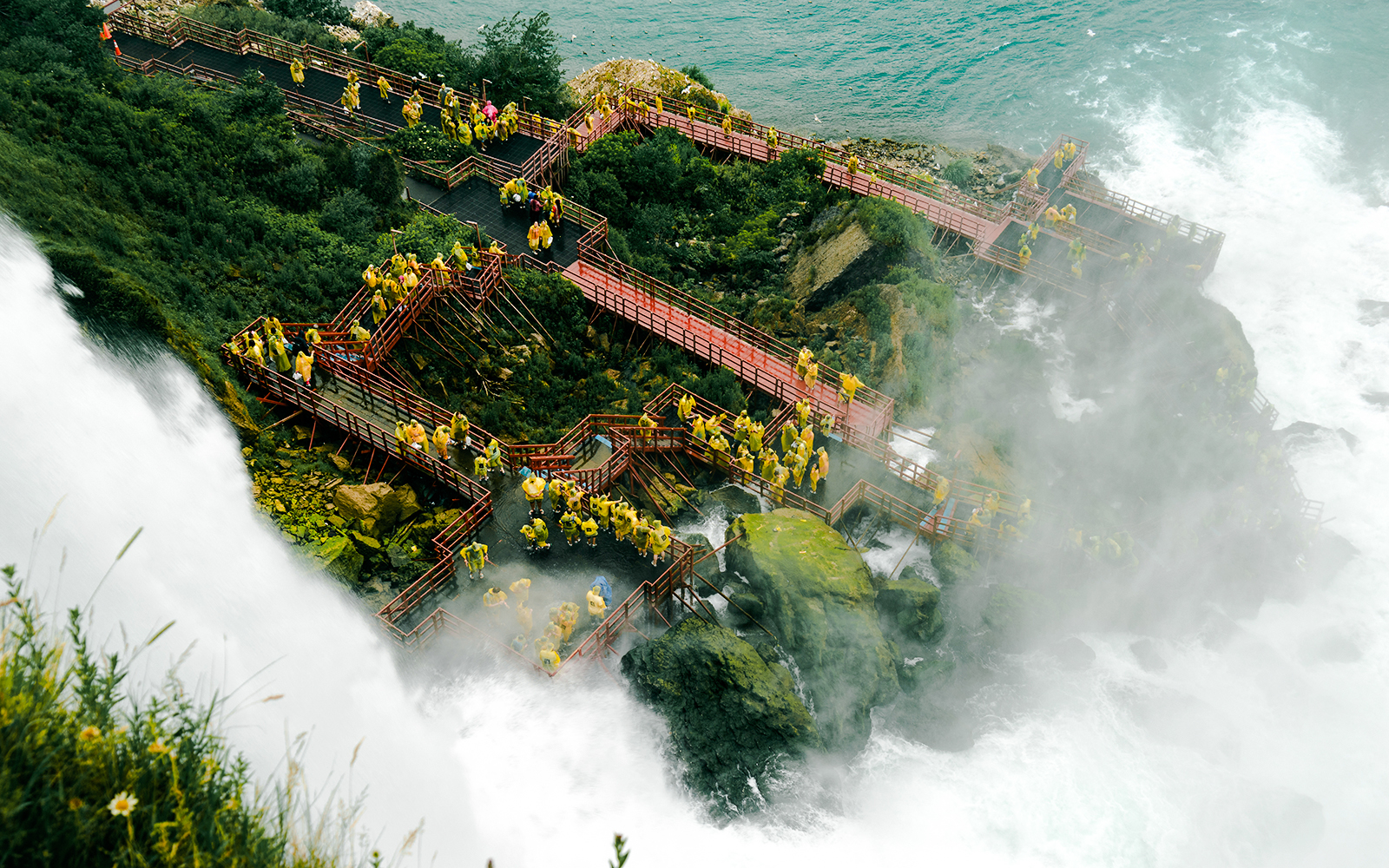 Visitors in raincoats on wooden walkways at Cave of the Winds, Niagara Falls.