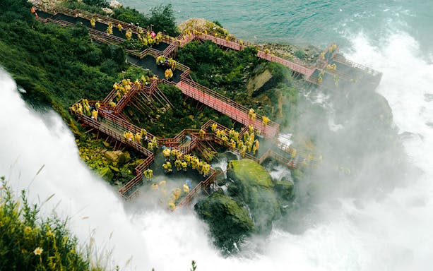 Visitors in raincoats on wooden walkways at Cave of the Winds, Niagara Falls.