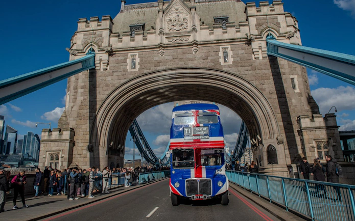 Double-decker bus crossing Tower Bridge on Central London afternoon tea tour.