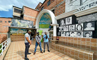 Family at Inflexión Memorial Park, Medellín, Colombia, with murals and portraits in the background.